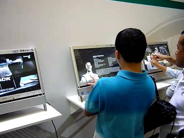 Visitors using Petronas multitouch screens showing Mercedes GP team information